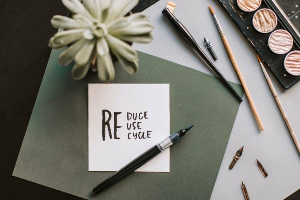 sticky note on table that reads reduce, reuse, recycle